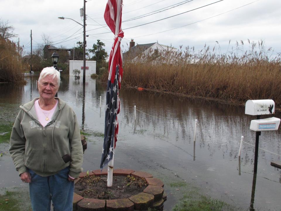 Joanne Kalb stands next to an American flag outside her home as floodwaters from a superstorm that struck the northeast begin to recede on Wednesday, Oct. 31, 2012, in Mastic Beach, N.Y. A Suffolk County official said the community on Long Island's south shore was among the hardest hit.(AP Photo/Frank Eltman)