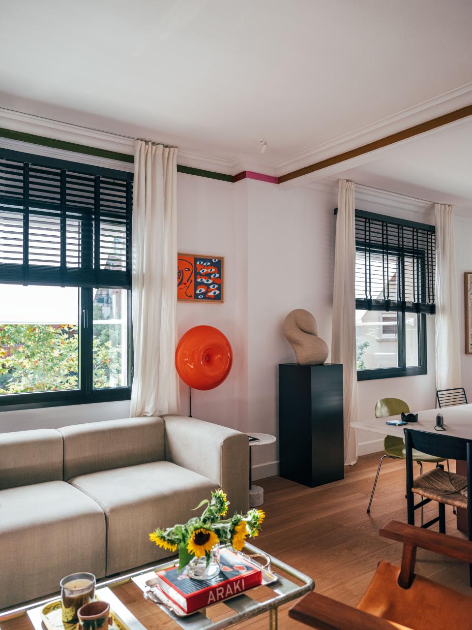 Artwork by Tom Polo hangs above an architectural light by Artemide, and a sculpture by Berta-Blanca T. Ivanow is displayed on a modern pedestal.