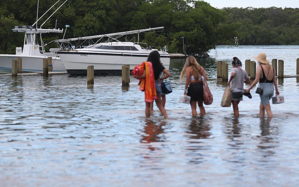 People walk to their boat through a flooded parking lot at the Haulover Marine Center before the arrival of Hurricane Dorian on Aug. 30, 2019 in Miami Beach, Fla. The high water was due to King tide which may cause additional problems as Hurricane Dorian arrives in the area as a possible Category 4 storm along the Florida coast.