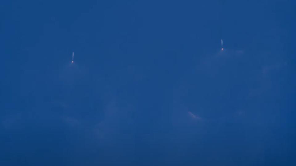 a big white rocket launches through a clear blue sky