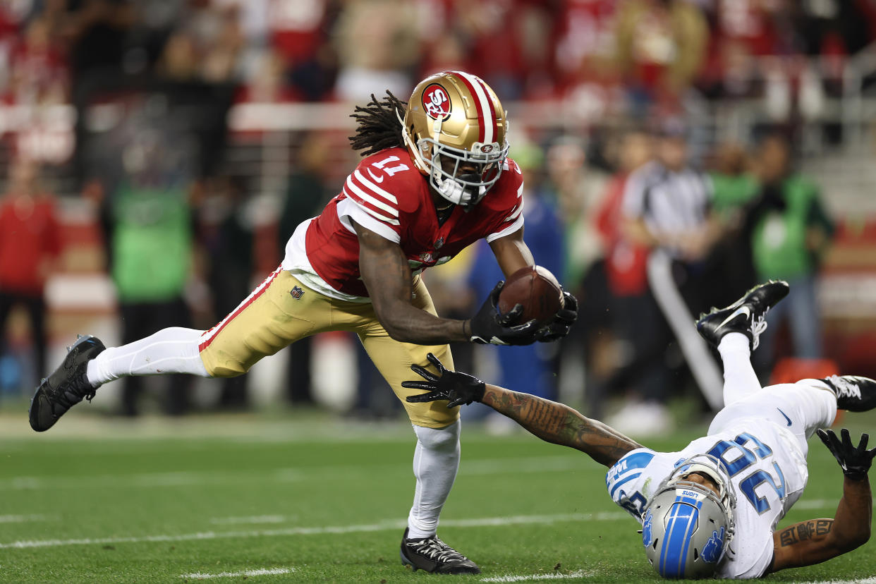 Brandon Aiyuk, receptor de los San Francisco 49ers, atrapa un balón que pegó en la careta de  Kindle Vildor, de los Detroit Lions, en el Juego de Campeonato de la NFC. (Foto de Ezra Shaw/Getty Images)