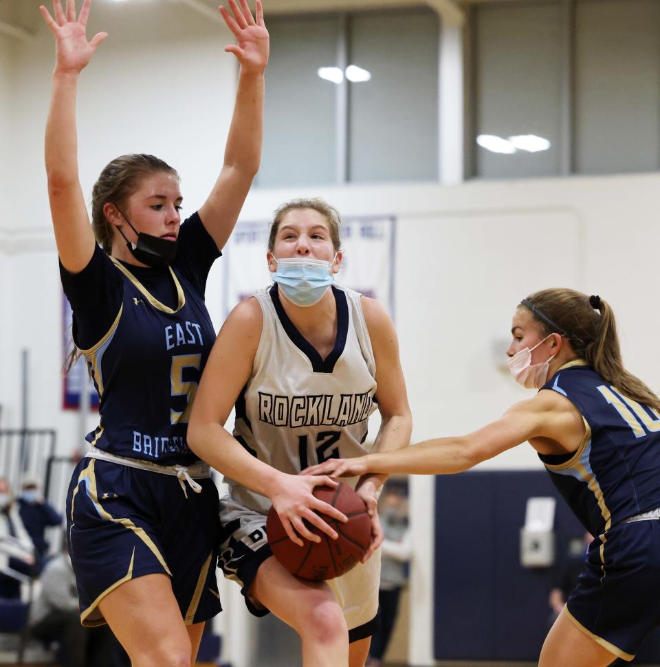 Rockland's Maggie Elie drives to the basket between East Bridgewater defenders Sophie Bradbury, left, and Erin Condon,   during a game on Tuesday, Jan. 18, 2022.  