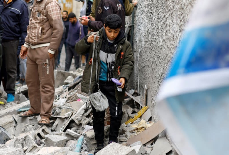 Palestinians walk at the site of an Israeli strike, in Rafah