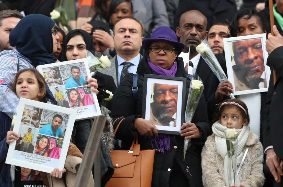 People hold photographs of their loved ones who were victims of the fire as they leave the Grenfell Tower National Memorial Service at St. Paul's Cathedral in London.