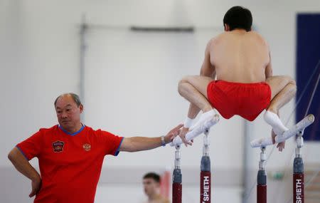 Coach of the gymnastics Russian Olympic team Valery Alfosov and team member Nikolai Kuksenkov (R) attend a training session at the Ozero Krugloe (Round Lake) training centre outside Moscow, Russia, July 21, 2016. REUTERS/Sergei Karpukhin