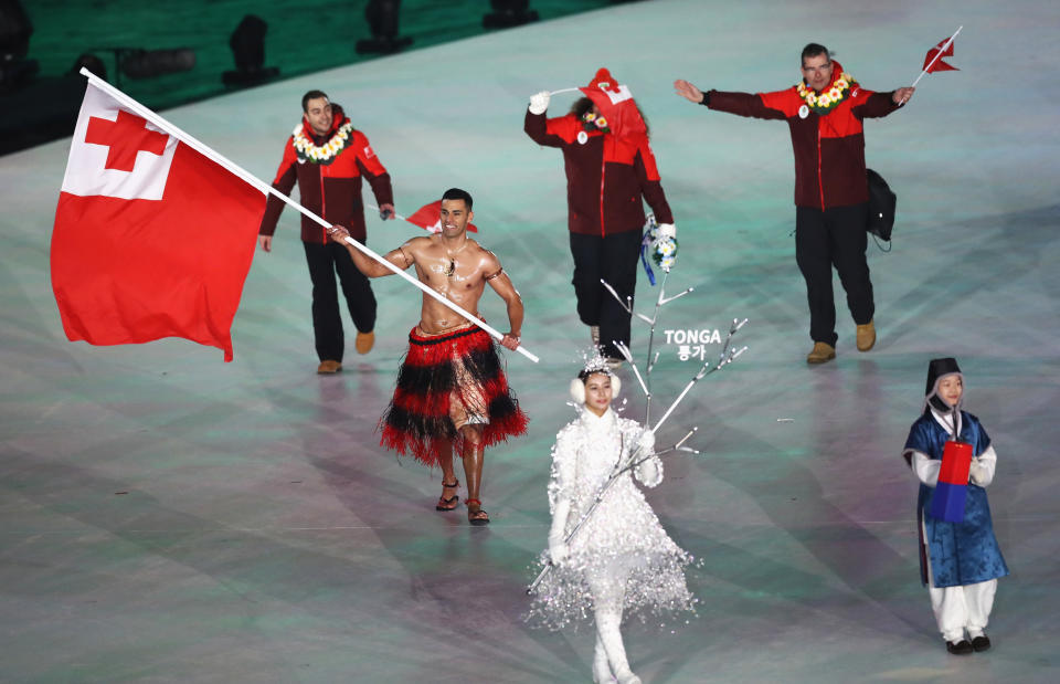 <p>Flag bearer Pita Taufatofua of Tonga leads the team — shirtless — while his teammates wear red zip jackets and black pants during the opening ceremony of the 2018 PyeongChang Games. (Photo: Ronald Martinez/Getty Images) </p>