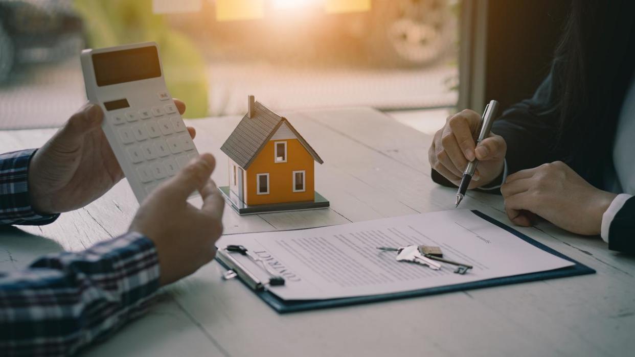 Real estate professionals offer their clients contracts to discuss home purchases, insurance or real estate loans. Home sales agents sit at the office with new home buyers in the office.