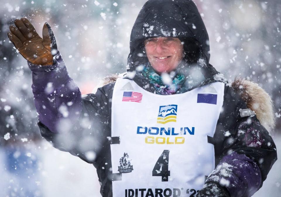 Canadian musher Michelle Phillips waves to the crowd as she takes off down Fourth Street during the ceremonial start of the Iditarod Trail Sled Dog Race in Anchorage, Alaska, March 5, 2022 (AP)