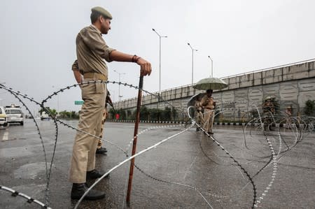 Indian security personnel stand guard along a deserted street during restrictions in Jammu