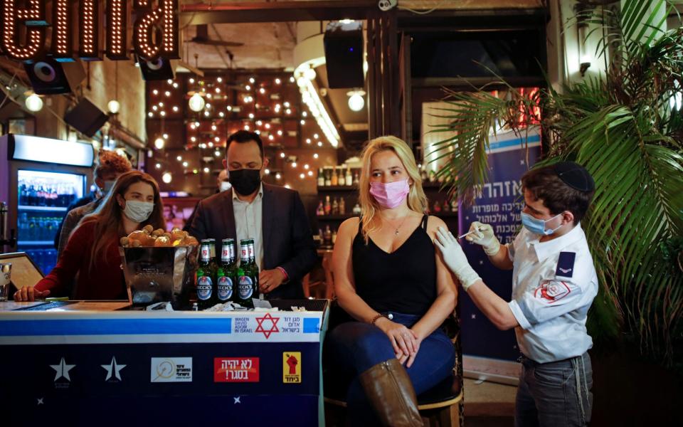 A woman receives a vaccination as part of a Tel Aviv municipality initiative offering a free drink at a bar to residents getting the shot - Reuters