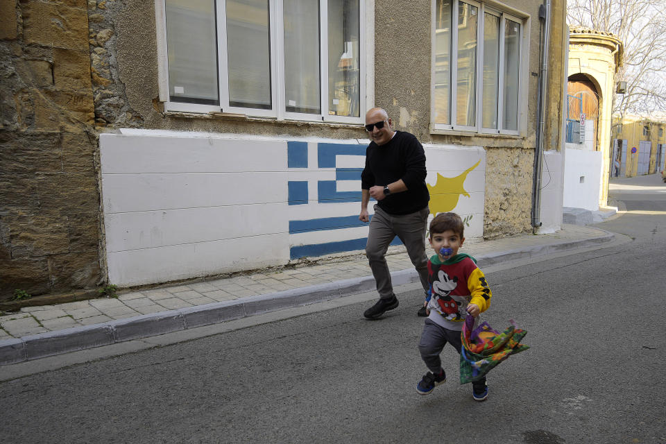 A man and boy run outside of a military guard post across the U.N. buffer zone that divides the Greek Cypriots of the south and the Turkish occupied area of the north in Nicosia, Cyprus, Saturday, Jan. 28, 2023. Cypriots are voting Sunday for a new president who they’ll expect to decisively steer the small island nation through shifting geopolitical sands and uncertain economic times that have become people's overriding concern, eclipsing stalemated efforts to remedy the country’s ethnic division. (AP Photo/Petros Karadjias)