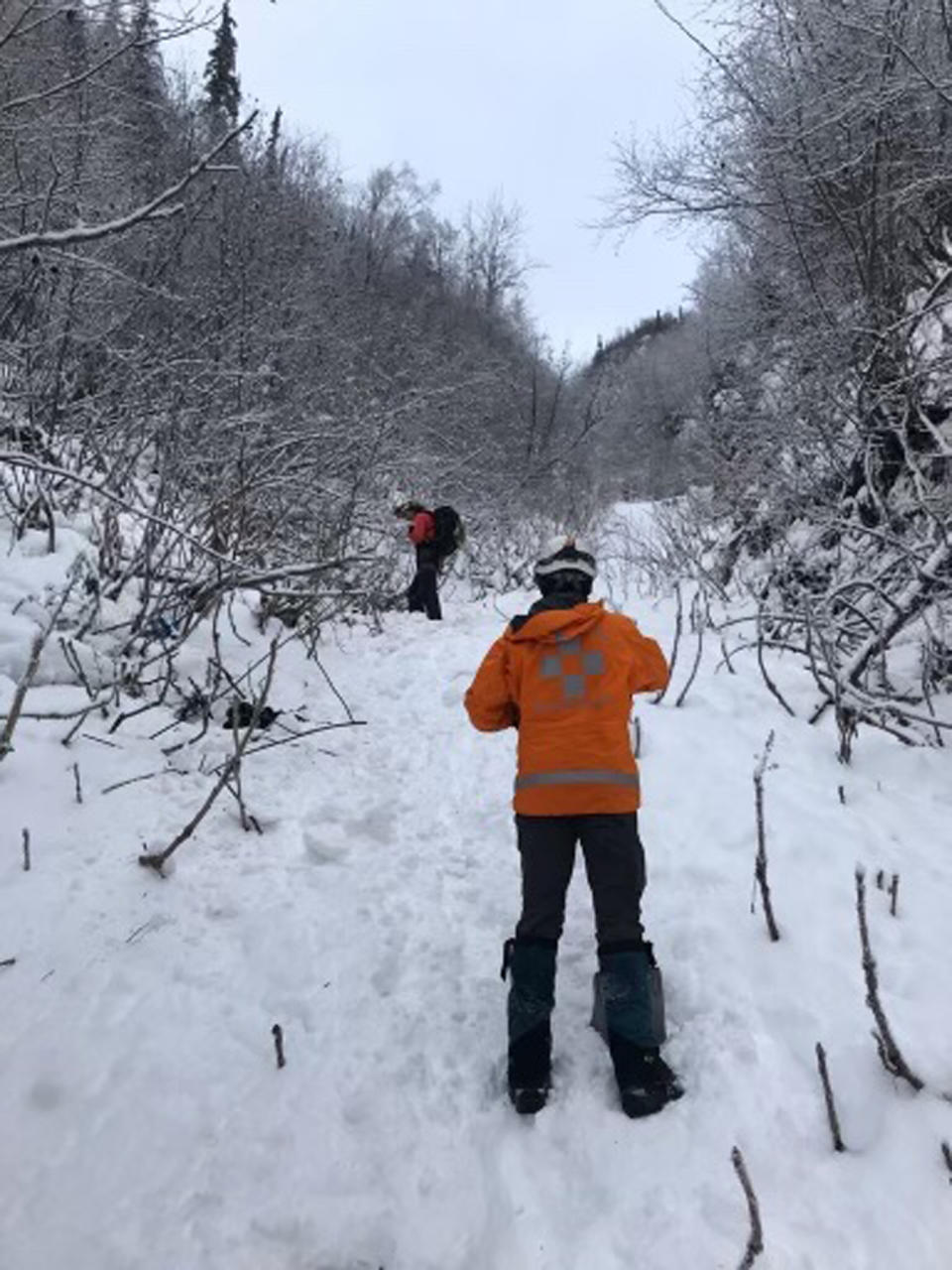 In this Feb. 3, 2021, photo provided by Matt Helm of the Alaska Mountain Rescue Group, two volunteers are shown after an avalanche in the Bear Mountain area near Chugiak, Alaska. The rescue group and troopers found the bodies of three hikers in the avalanche slide. (Matt Helm/Alaska Mountain Rescue Group via AP)