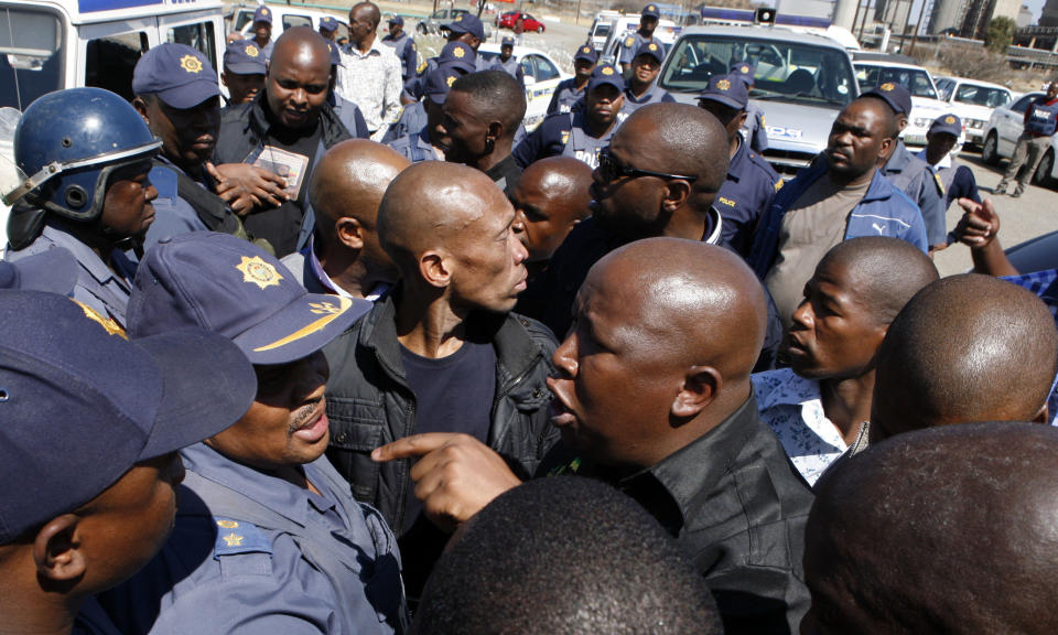 Firebrand politician Julius Malema, right argues with police officers, at Lonmin Platinum Mine near Rustenburg, South Africa, Monday, Sept. 17, 2012. London-registered Lonmin PLC announced it is halting construction of a new shaft, putting 1,200 people out of work, as the bloody and bitter strike at its beleaguered South African platinum mine dragged on its fifth week. The strikes that have halted work at seven gold and platinum mines have spread to the chrome sector, according to the official South African Press Association. Meanwhile, police blocked rabblerousing politician Julius Malema from addressing some 3,000 strikers gathered at a stadium at the Lonmin mine at Marikana, northwest of Johannesburg. (AP Photo/Themba Hadebe)