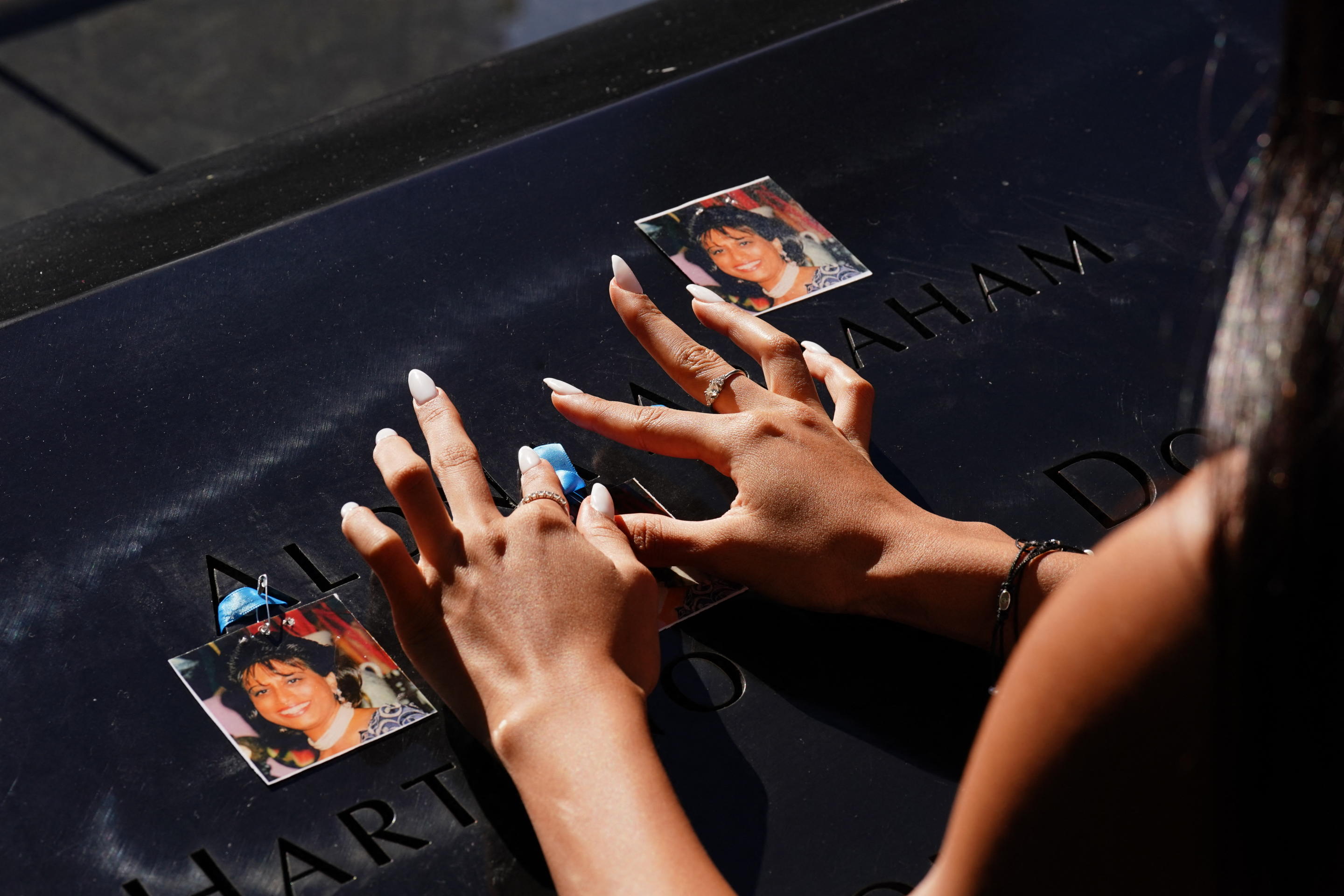 A woman places photos of a relative on the 9/11 memorial. 