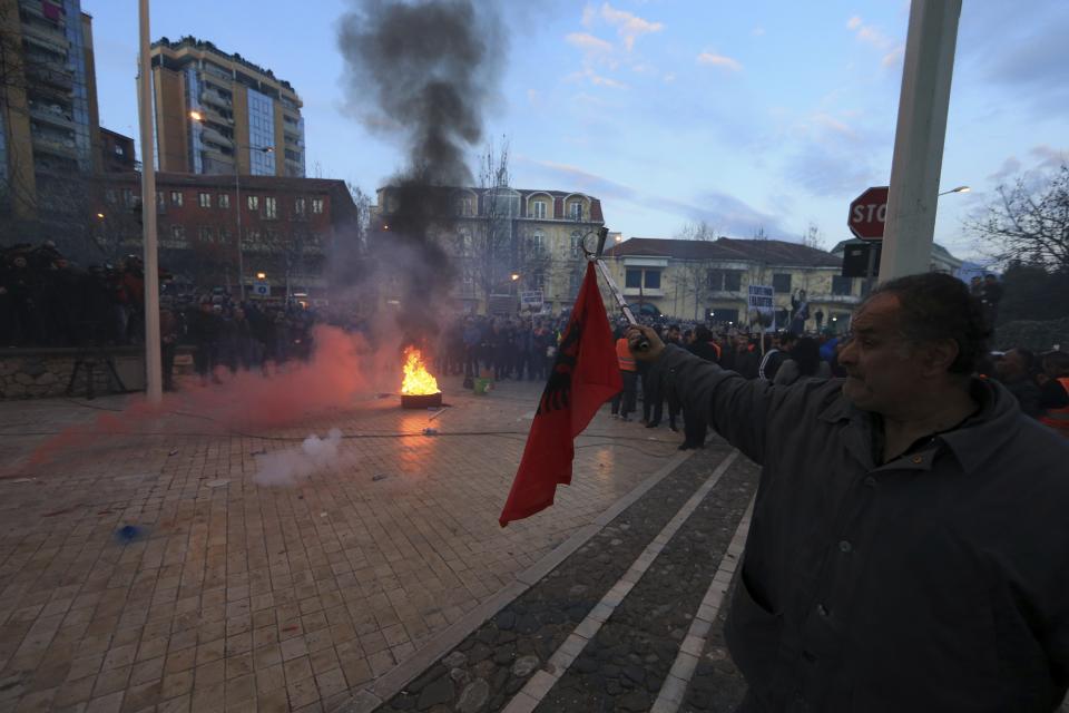 A protester holds an Albanian flag during an antigovernment rally in Tirana, Tuesday, Feb. 26, 2019. Albanian opposition supporters have surrounded the parliament building and are demanding that the government resign, claiming it's corrupt and has links to organized crime. (AP Photo/Hektor Pustina)