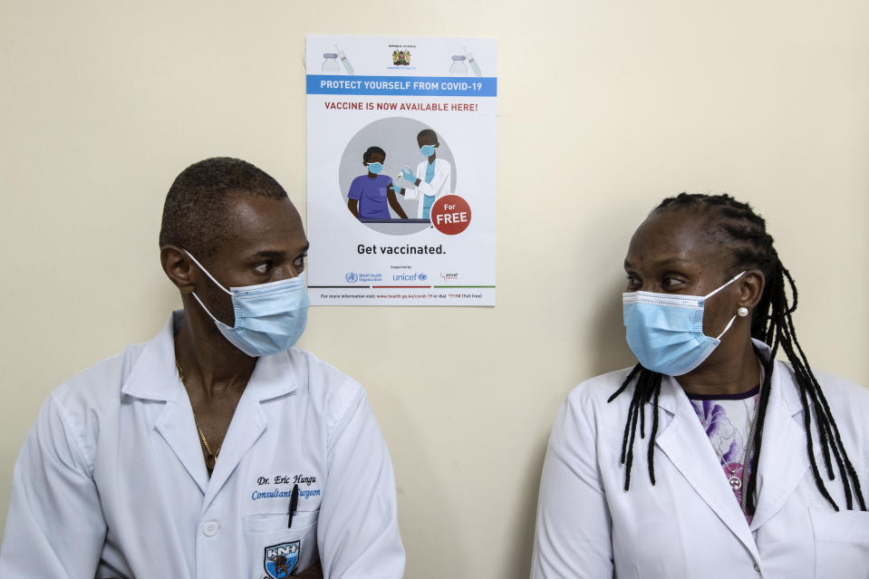 FILE - In this March 5, 2021, file photo, consultant surgeon Dr. Eric Hungu, left, and Senior Lecturer Dr. Marybeth Maritim, right, wait in line to receive some of the country’s first doses of the AstraZeneca vaccine, provided through the global COVAX initiative, at Kenyatta National Hospital in Nairobi, Kenya. The suspension of the AstraZeneca vaccine in several European countries could fuel skepticism about the shot far beyond their shores, potentially threatening the rollout of a vaccine that is key to the global strategy to stamp out the coronavirus pandemic, especially in developing nations. (AP Photo/Ben Curtis, File)