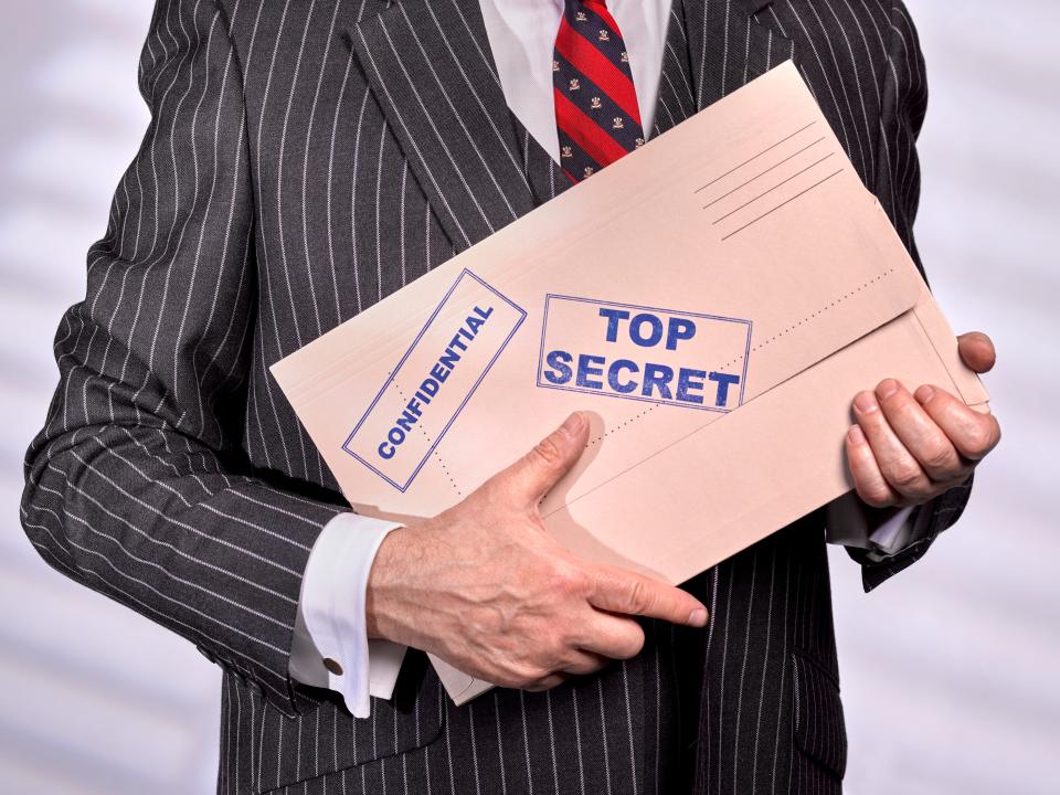 A man holds a folder marked 'Top Secret'
