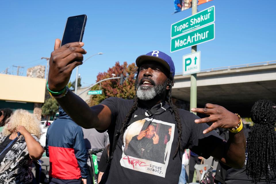 Randy Moore, of Los Angeles, poses beneath a new sign during a street renaming ceremony for Tupac Shakur on Friday. A stretch of street in Oakland, California, was renamed Tupac Shakur Way, 27 years after the hip-hop icon's murder.