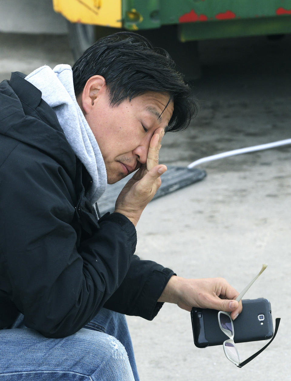 A relative of a passenger aboard the sunken Sewol ferry wipes his tears as he awaits news on his missing loved one at a port in Jindo, South Korea, Tuesday, April 22, 2014. As divers continue to search the interior of the sunken ferry, the number of confirmed deaths has risen, with over 200 other people still missing. (AP Photo/Ahn Young-joon)