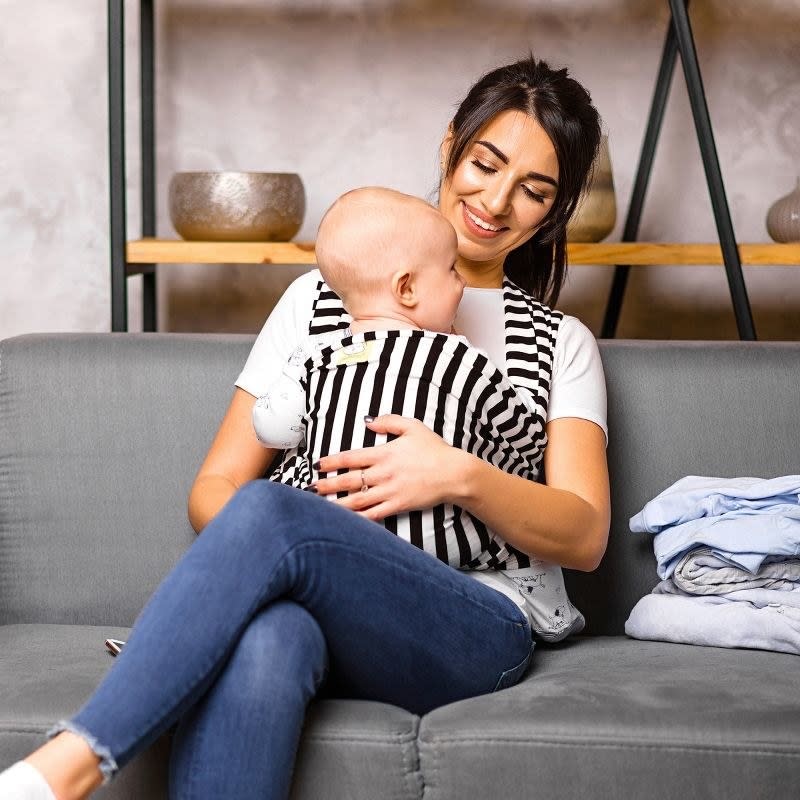 Woman holds baby in sling carrier