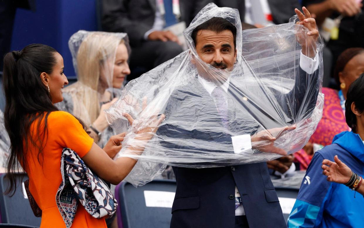 The Emir of Qatar , Sheikh Tamim bin Hamad al-Thani, struggling with a poncho