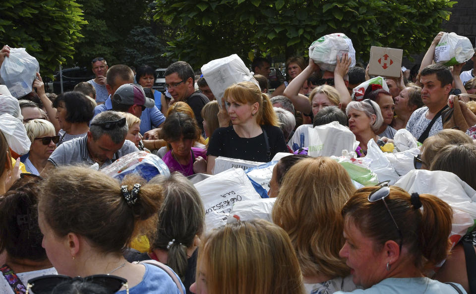 FILE - Local residents, many of whom fled the war, gather to hand out donated items such as medicines, clothes, and personal belongings to their relatives on the territories occupied by Russia, in Zaporizhzhia, Ukraine, on Aug. 14, 2022. According to Russian state TV, the future of the Ukrainian regions occupied by Moscow's forces is all but decided: Referendums on becoming part of Russia will soon take place there, and the joyful residents who were abandoned by Kyiv will be able to prosper in peace. In reality, the Kremlin appears to be in no rush to seal the deal on Ukraine's southern regions of Kherson and Zaporizhzhia and the eastern provinces of Donetsk and Luhansk. (AP Photo/Andriy Andriyenko)