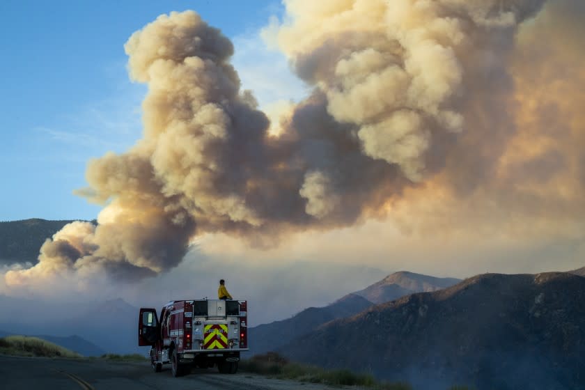 A firefighter from Carpinteria monitors a huge plume of smoke from the Apple fire along Bluff Street, north of Banning.