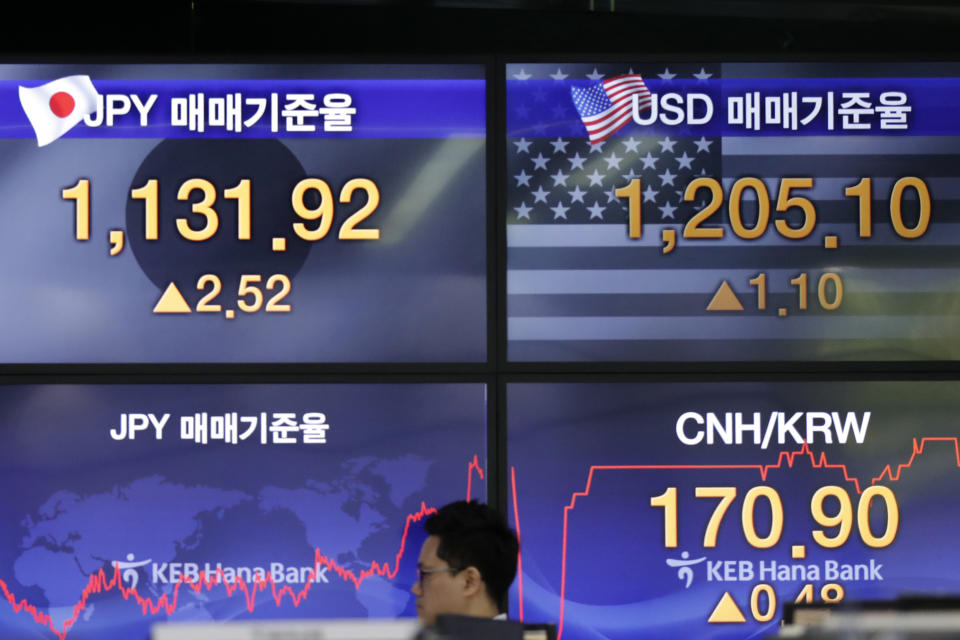 A currency trader walks by screens showing the foreign exchange rates at the foreign exchange dealing room in Seoul, South Korea, Friday, Aug. 23, 2019. Asian stock markets were mixed on Friday after Wall Street declined ahead of a closely watched speech by the U.S. Federal Reserve chairman. (AP Photo/Lee Jin-man)