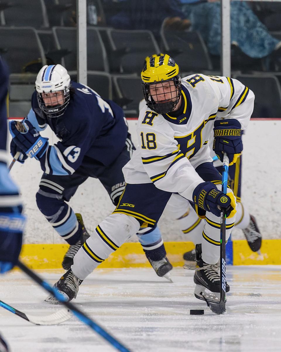 Hartland's Jack L'Esperance (18) carries the puck while pursued by Livonia Stevenson's Andrew Clark during the Eagles' 4-3 victory Wednesday, Jan. 18, 2023.