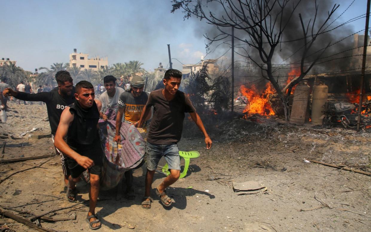 People carry a casualty at the site of what Palestinians say was an Israeli strike at a tent camp in al-Mawasi