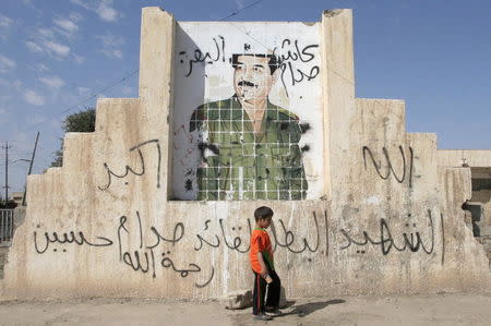 A boy walks past a picture of Iraq's former president Saddam Hussein on a street in Tikrit, Iraq in this March 20, 2007 file photo. REUTERS/Nuhad Hussin/Files