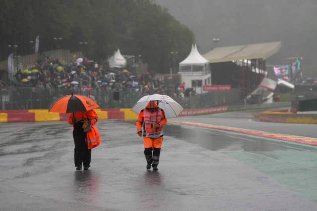 Stewards walk on the track during a rain delay at the Formula One Grand Prix at Spa-Francorchamps, where only two laps were eventually completed