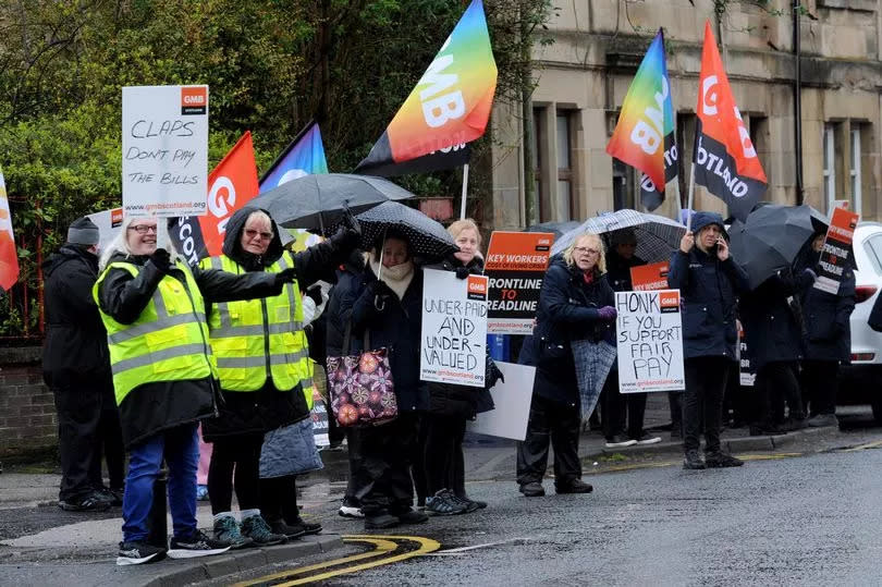 Renfrewshire carers wave placards and flags as they stand on a picket line in Paisley