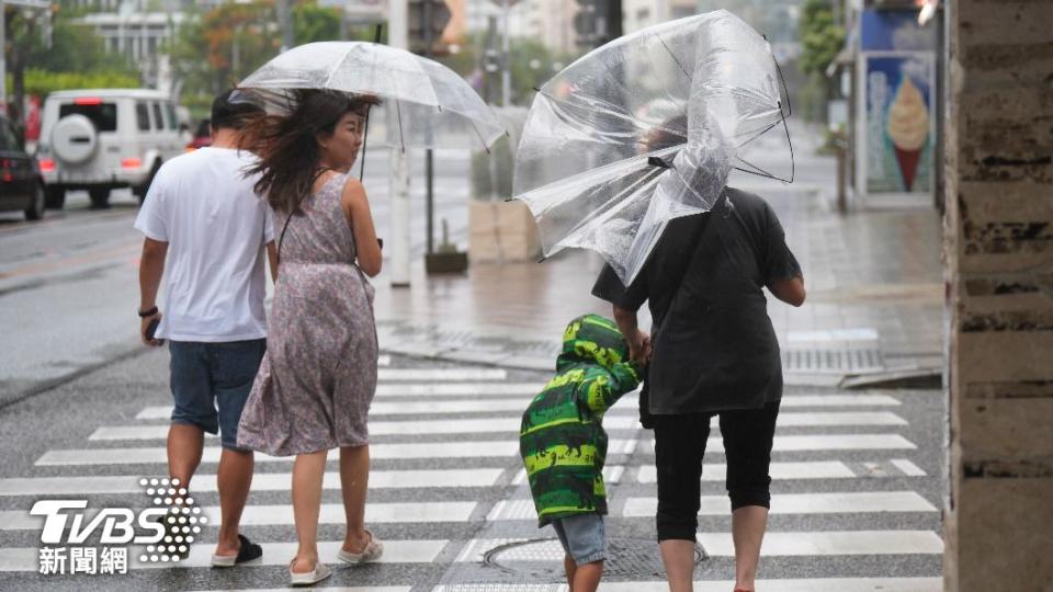 首當其衝的沖繩，民眾撐著的傘已經被風吹到無法使用。（圖／達志影像美聯社）