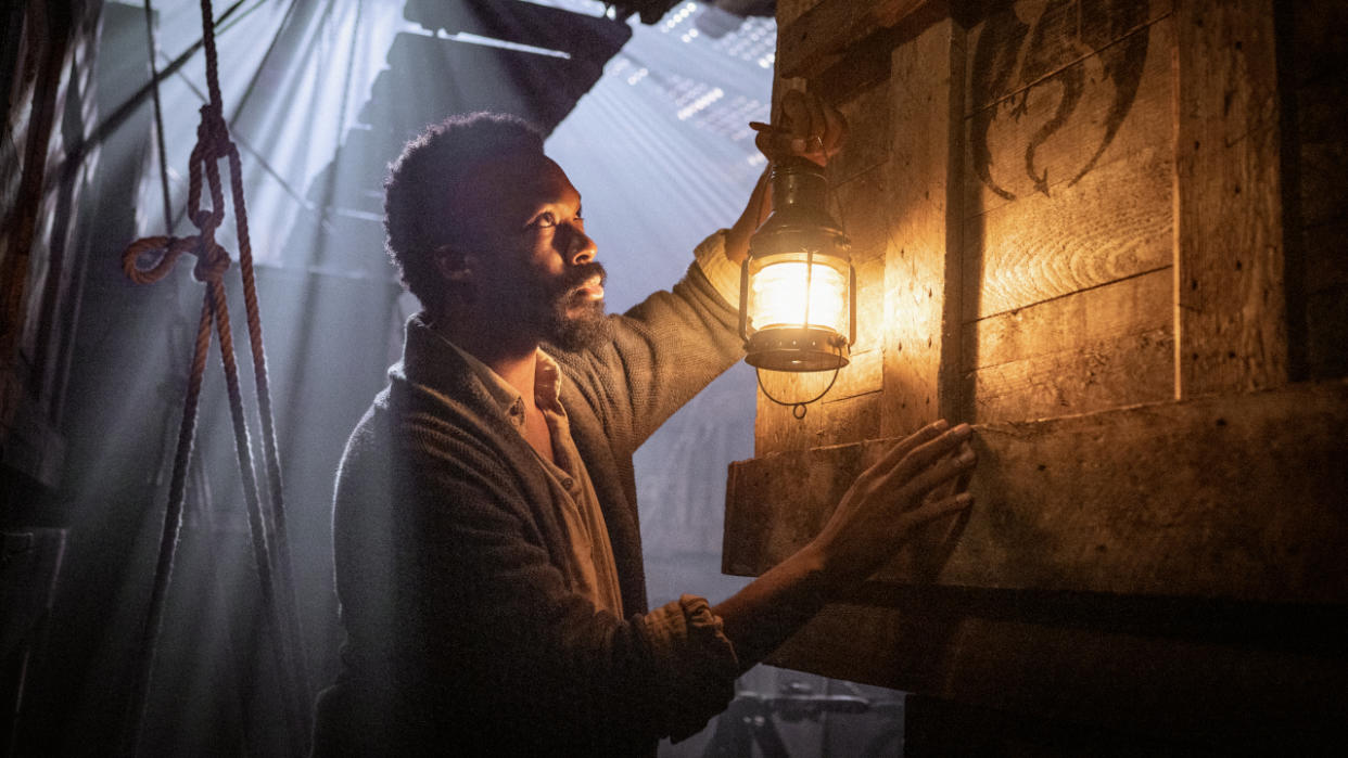  Corey Hawkins examines a crate by lantern light in The Last Voyage of the Demeter. 