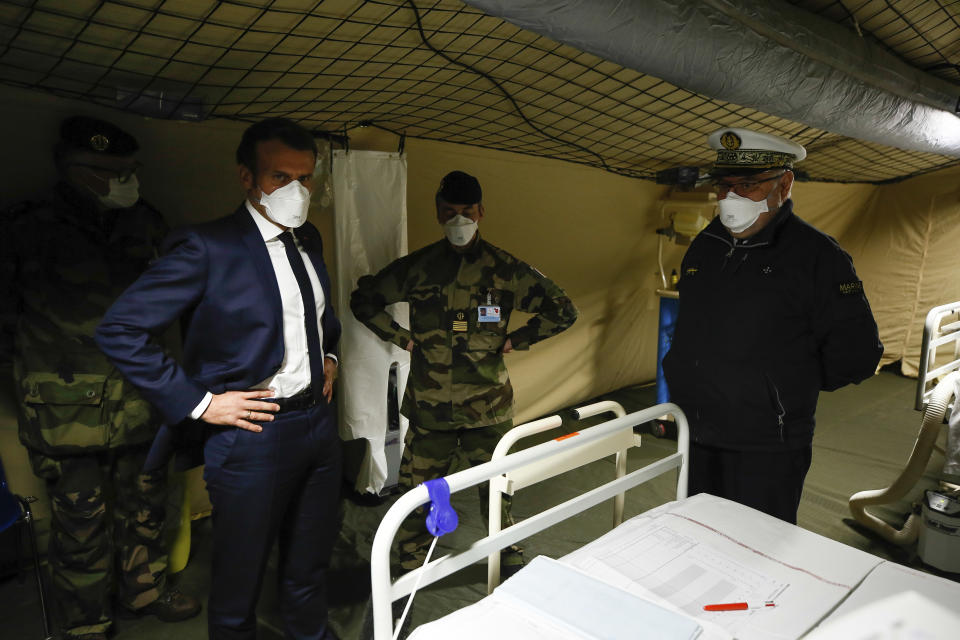 French President Emmanuel Macron, second left, wears a face mask as he visits the military field hospital in Mulhouse, eastern France, Wednesday, March 25, 2020. French President Emmanuel Macron launched a special military operation Wednesday to help fight the new virus in one of the world's hardest-hit countries. The new coronavirus causes mild or moderate symptoms for most people, but for some, especially older adults and people with existing health problems, it can cause more severe illness or death. (Mathieu Cugnot/Pool via AP)