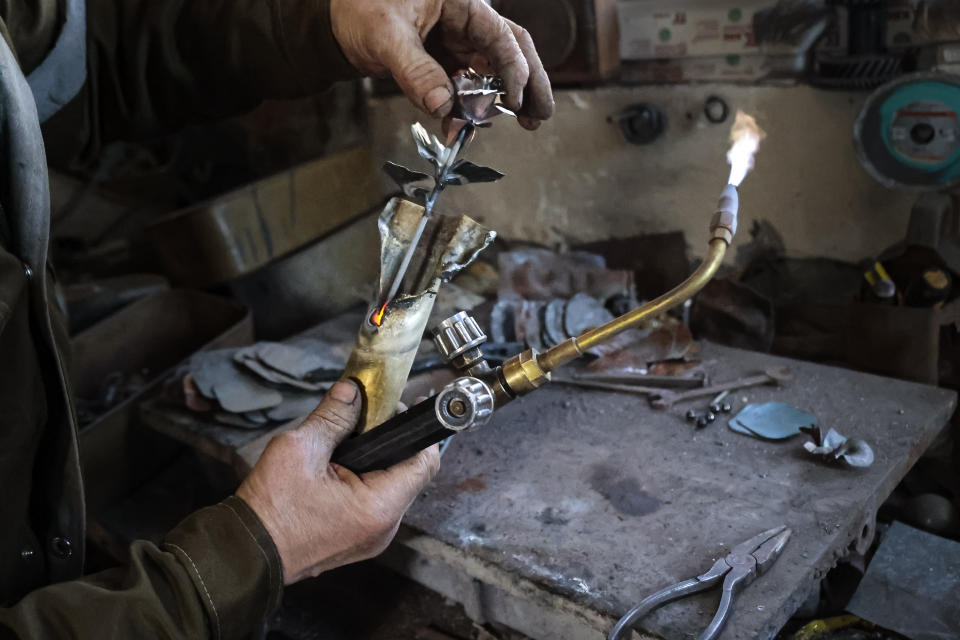 Viktor Mikhalev works in a workshop in his house in Donetsk, Russian-controlled Donetsk region, eastern Ukraine, Saturday, March 4, 2023. Mikhalev is transforming weapons and ammunition into flowers of war. Mikhalev, trained as a welder, lives and works in a house whose fence and door are decorated with forged flowers and grapes. (AP Photo/Alexei Alexandrov)