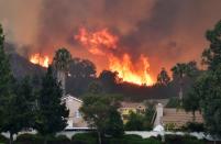 <p>Flames from the Holy Fire shoot up above homes in Lake Elsinore, California, southeast of Los Angeles on Aug. 10, 2018. (Photo: Robyn Beck/AFP/Getty Images) </p>