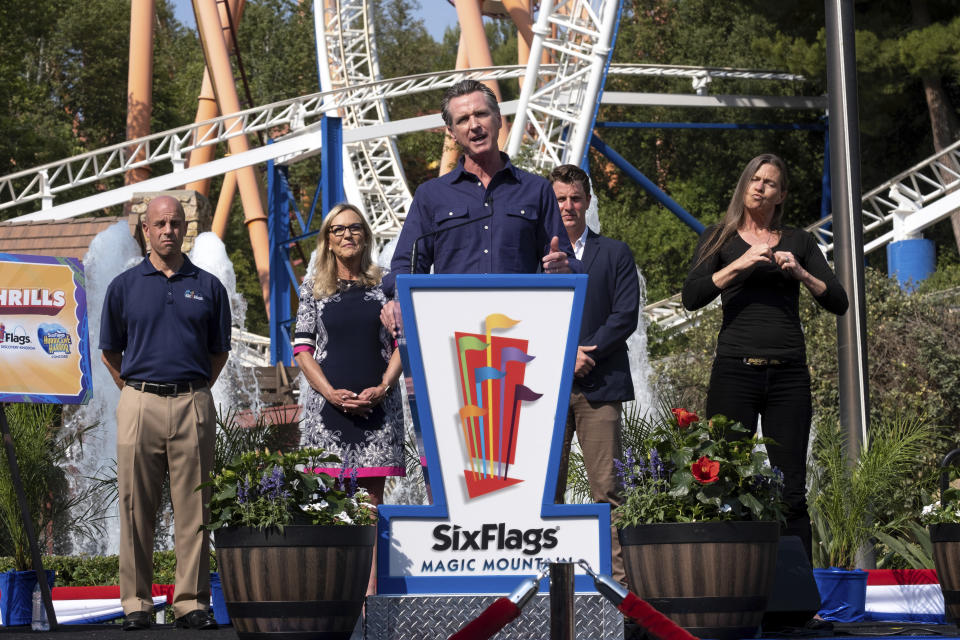 California Gov. Gavin Newsom welcomes the public to Six Flags Magic Mountain in Santa Clarita, Calif. on Wednesday, June 16, 2021. In the background, from left, are; Michael Spanos, President of Six Flags, LA county supervisor Kathryn Barger and state senator Henry Stern. Newsom continued his tour of the state after lifting most COVID-19 restrictions Tuesday. (David Crane/The Orange County Register via AP)