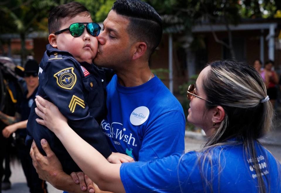 Franco Bernal, 6, battling childhood leukemia, left, receives hugs from his parents, Jorge, center, and Wendy after learning his Make-A-Wish to go to Disney World was granted on Thursday, July 18, 2024, with a parade by City of Miami Police in Miami.