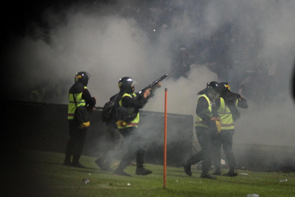 A riot police officer fires tear gas during a riot after the league BRI Liga 1 football match between Arema vs Persebaya at Kanjuruhan Stadium in Indonesia (via REUTERS)