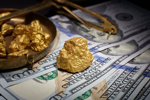 Gold nuggets on top of U.S. hundred-dollar bills.