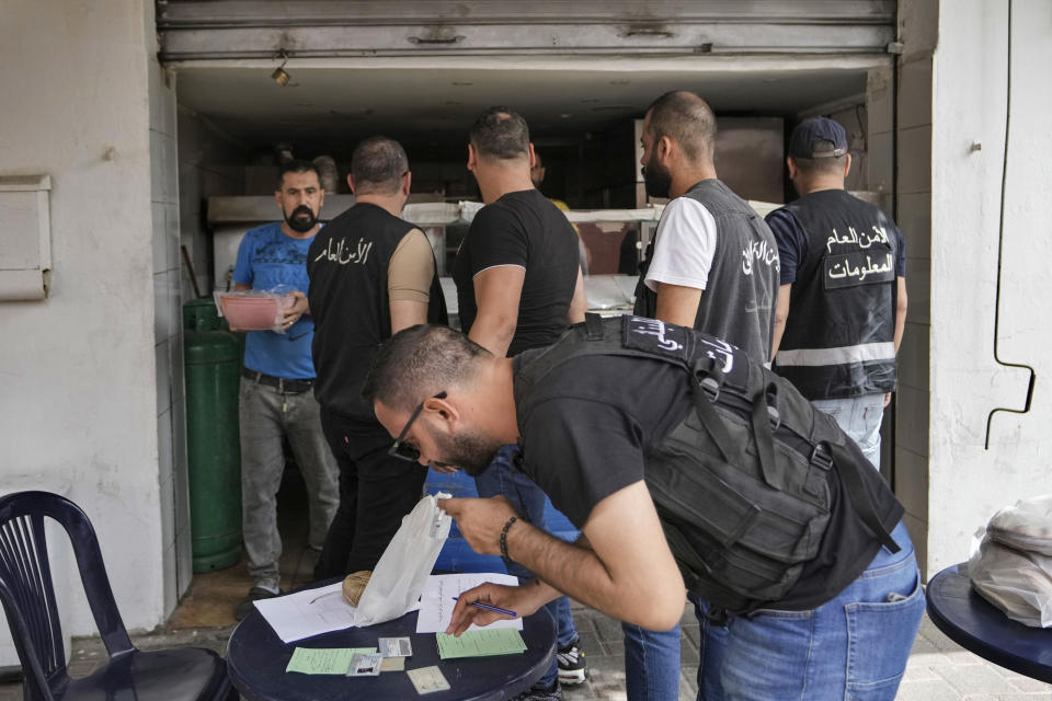 Lebanese General Security officers check the personal IDs of Syrian workers, as part of a crackdown on businesses employing unregistered Syrian workers in Beirut, Lebanon, Saturday, May 11, 2024. Hundreds of Syrians refugees left a remote northeastern Lebanese town back to Syria in a convoy Tuesday, amid a surge in anti-refugee sentiment in the small, crisis-hit country. The new push for repatriation comes as Lebanon's quarrelling ruling political parties have reached a rare consensus in recent years, all agreeing that Syrian refugees should be returned. (AP Photo/Hassan Ammar)