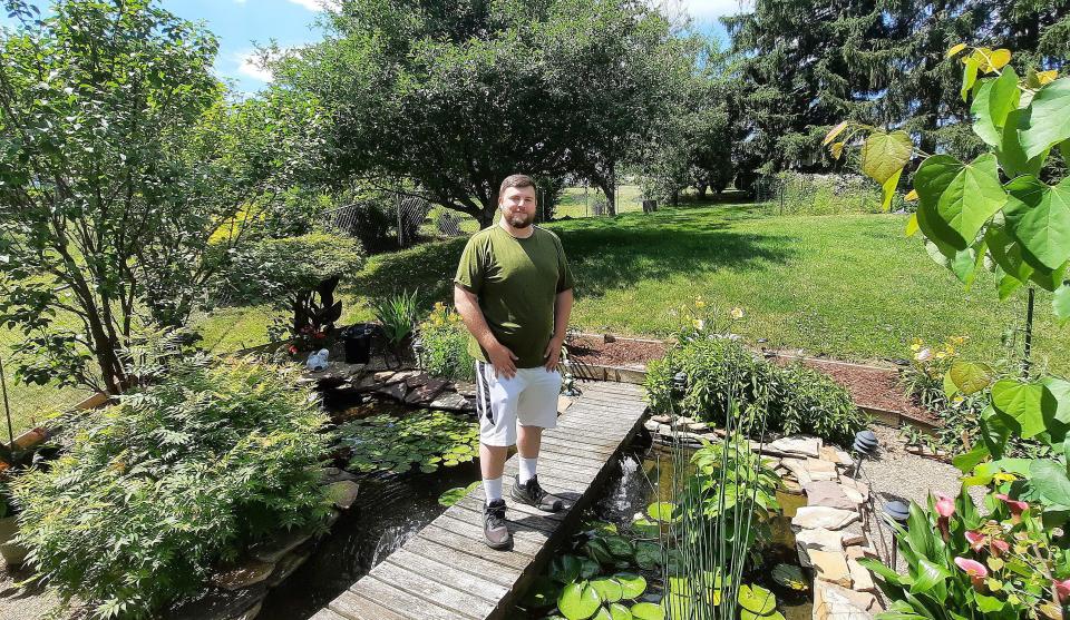 Aaron Capouellez stands on the bridge of his pond filled with aquatic life in Stonycreek Township on the border of Cambria and Somerset counties.