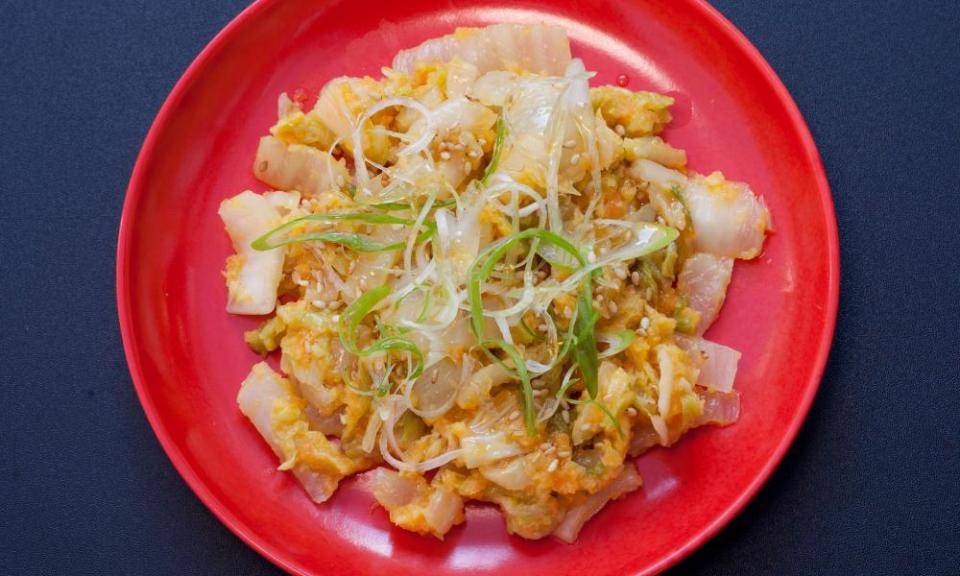 A round red plate with golden kimchi