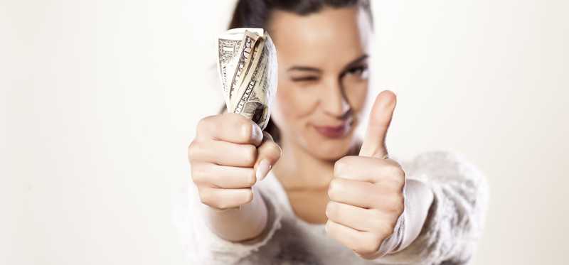 Woman giving thumbs up with other hand full of money.