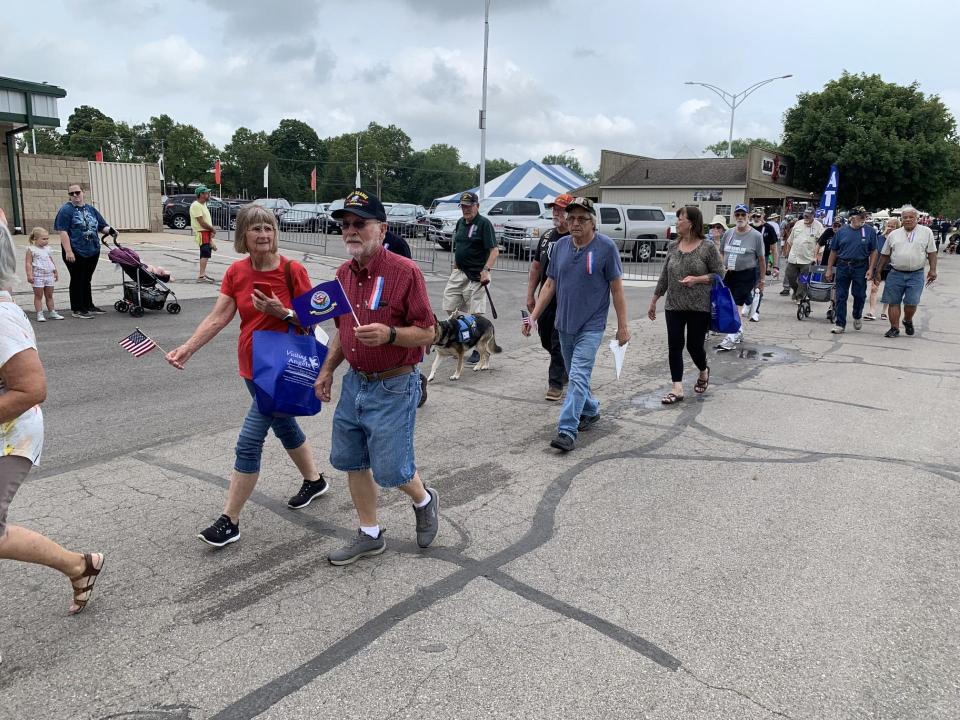 Ed Weaver, a member of Erie Post 3925, VFW, and Sharon Grodi, a member of the post auxiliary, walk in the Veterans Day procession at the Monroe County Fair Monday.