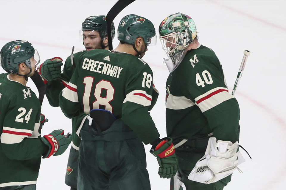 Minnesota Wild's Devan Dubnyk, right, is congratulated by Jordan Greenway and others after the Wild defeated the Detroit Red Wings 4-2 in an NHL hockey game Wednesday, Jan. 22, 2020, in St. Paul, Minn. Greenway scored a goal in the first period. (AP Photo/Jim Mone)