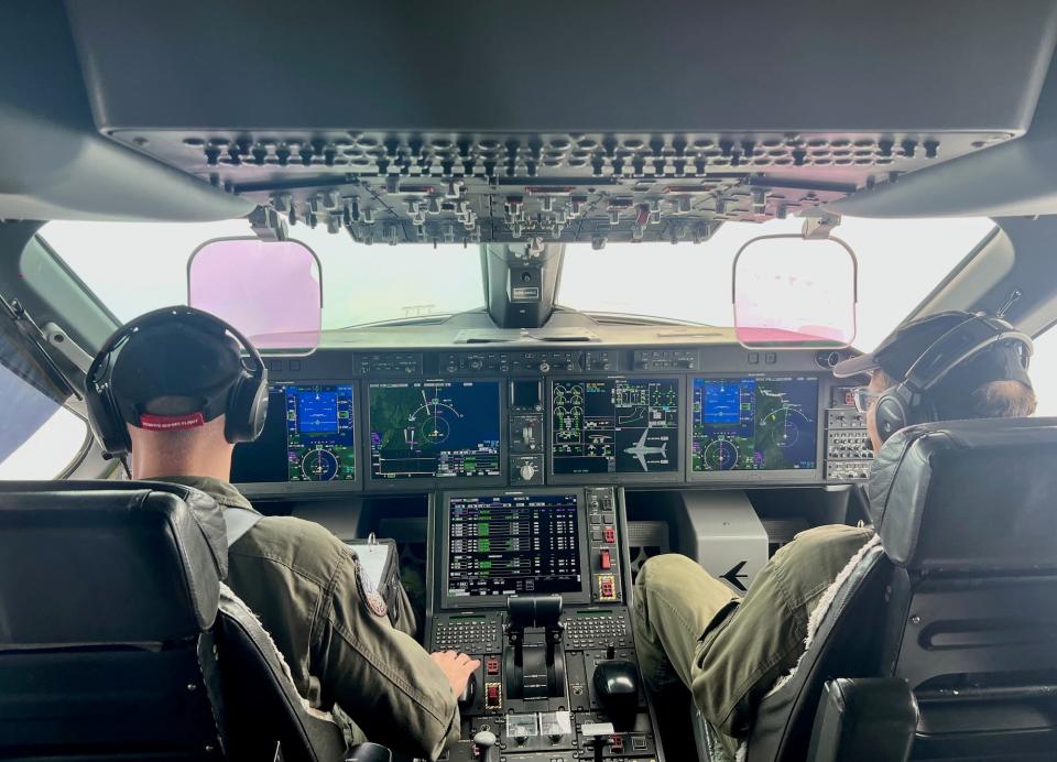 Two pilots sit in the cockpit of a C-390.