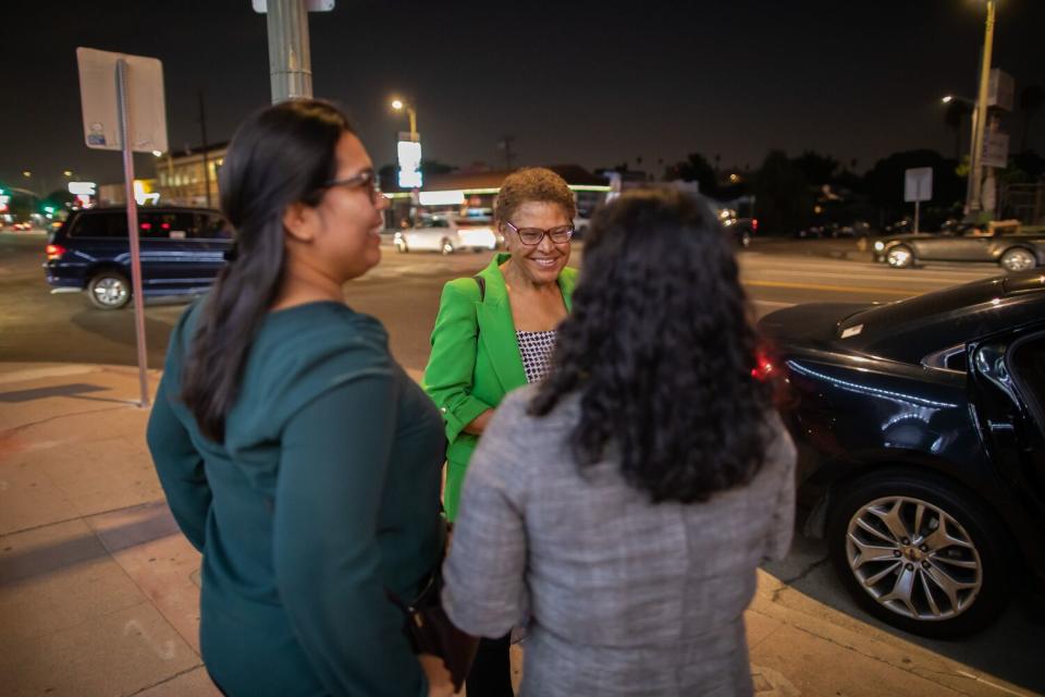 A smiling woman with two other women on a sidewalk.